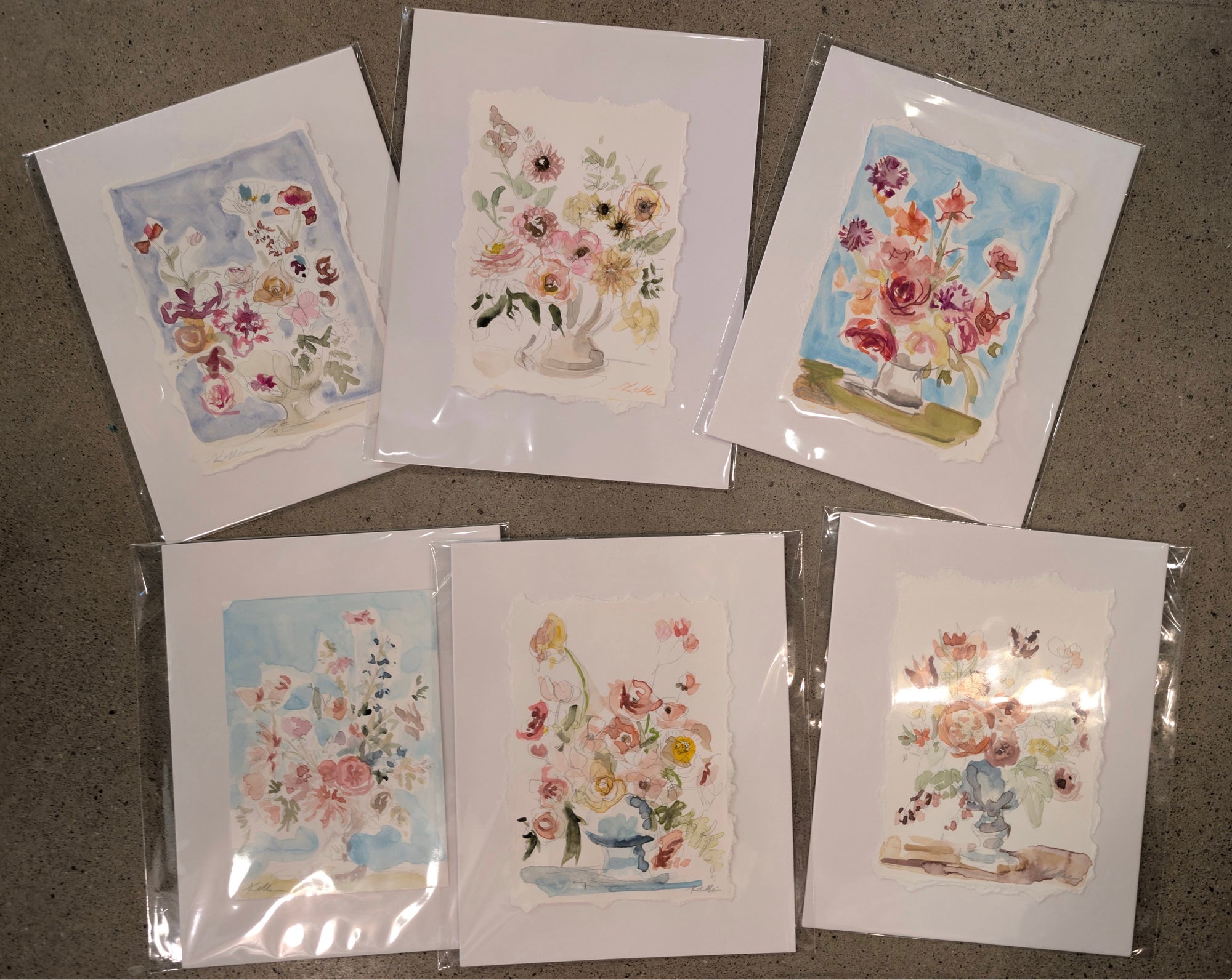 Set of floral greeting cards in clear packaging on a gray surface