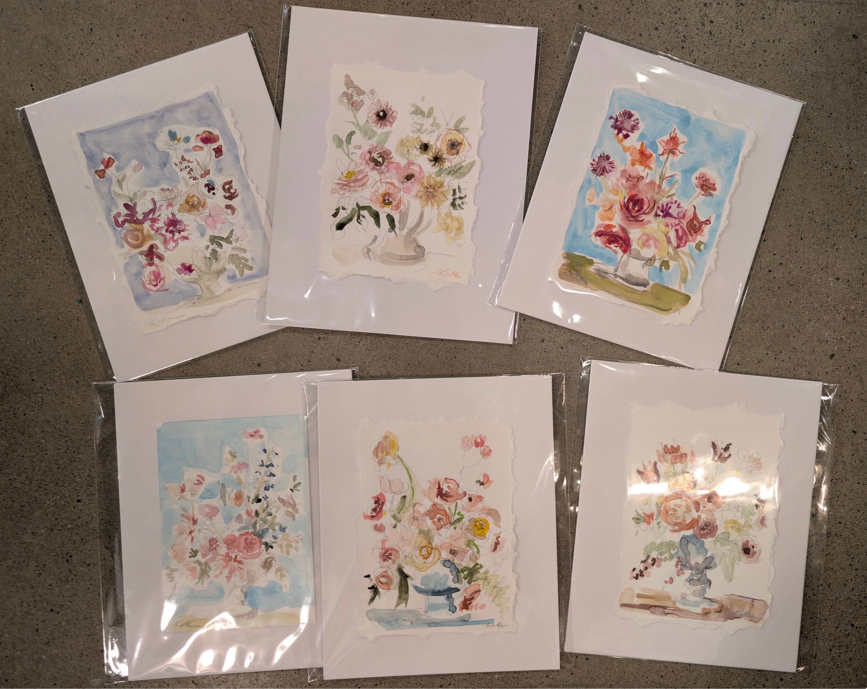 Set of floral greeting cards in clear packaging on a gray surface