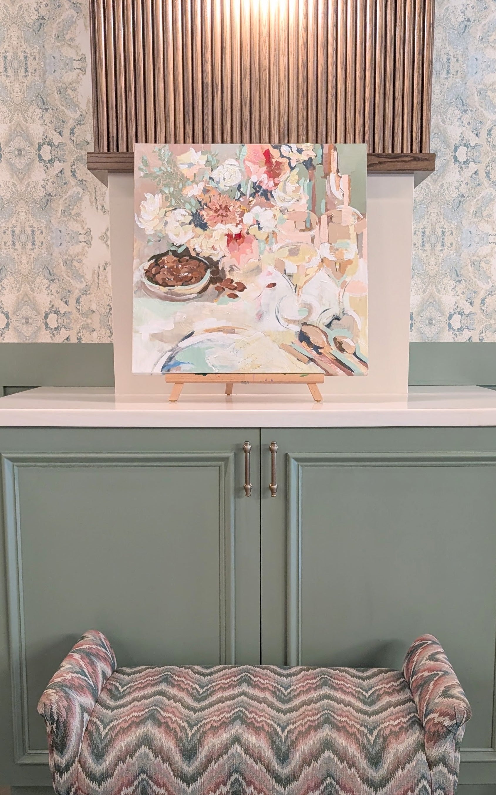 Decorative stool with a patterned seat in front of a kitchen counter with a floral backsplash.
